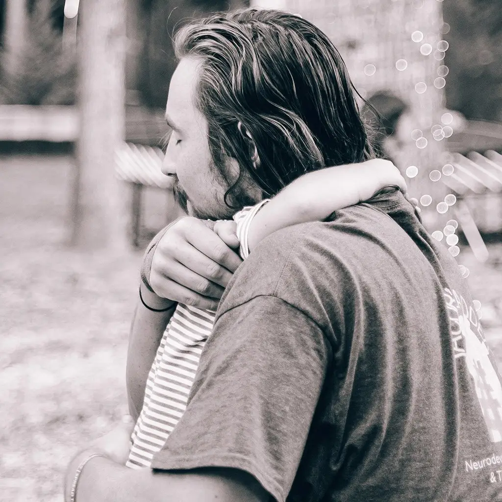 Child Development Therapy - Black and White Image of child hugging Parent.