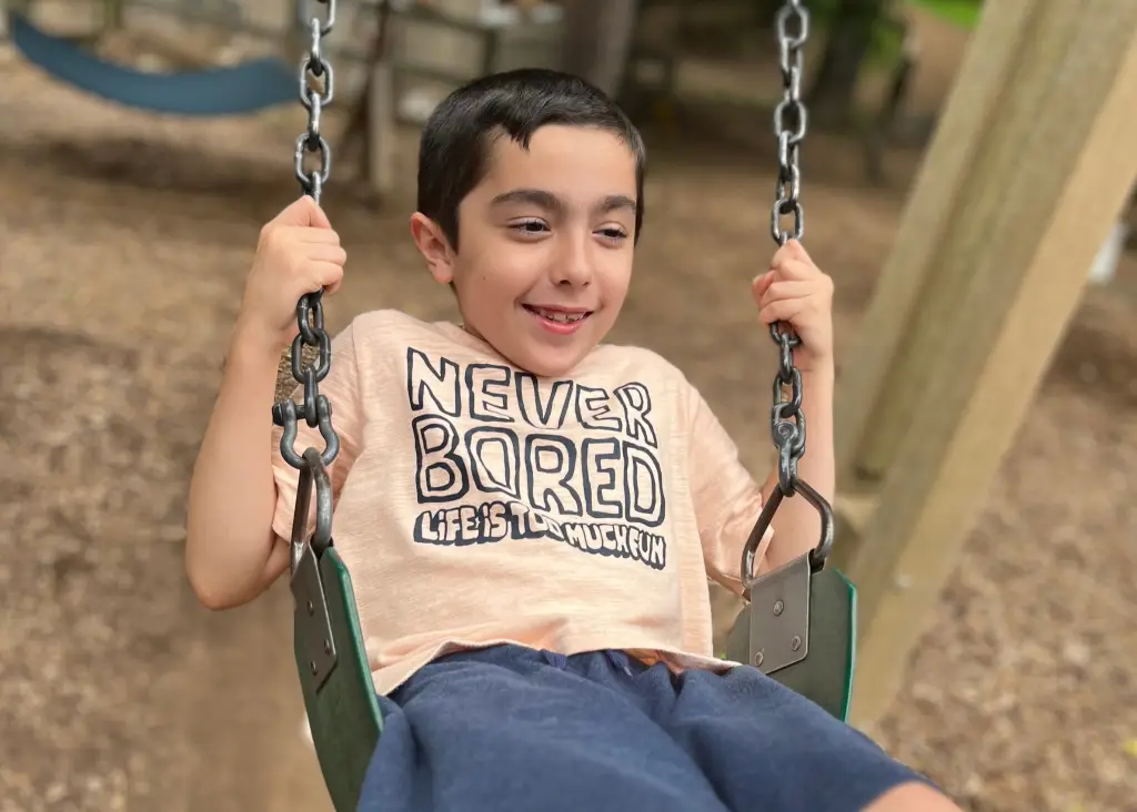 Mehdi Smiling On A Playground Swing During His Journey Of Growth, Confidence, And Connection At Jacob’s Ladder